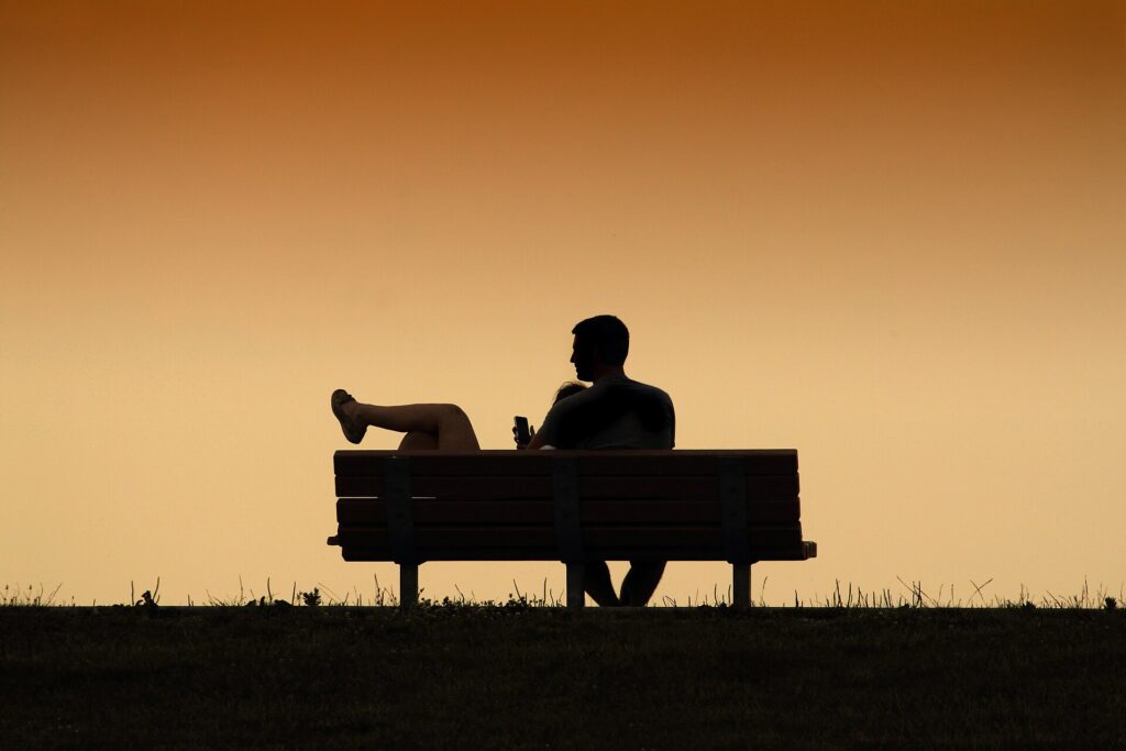 Two people sitting close together at sunset, symbolising love as the felt experience of non-separation in Ad Unum Energy Healing