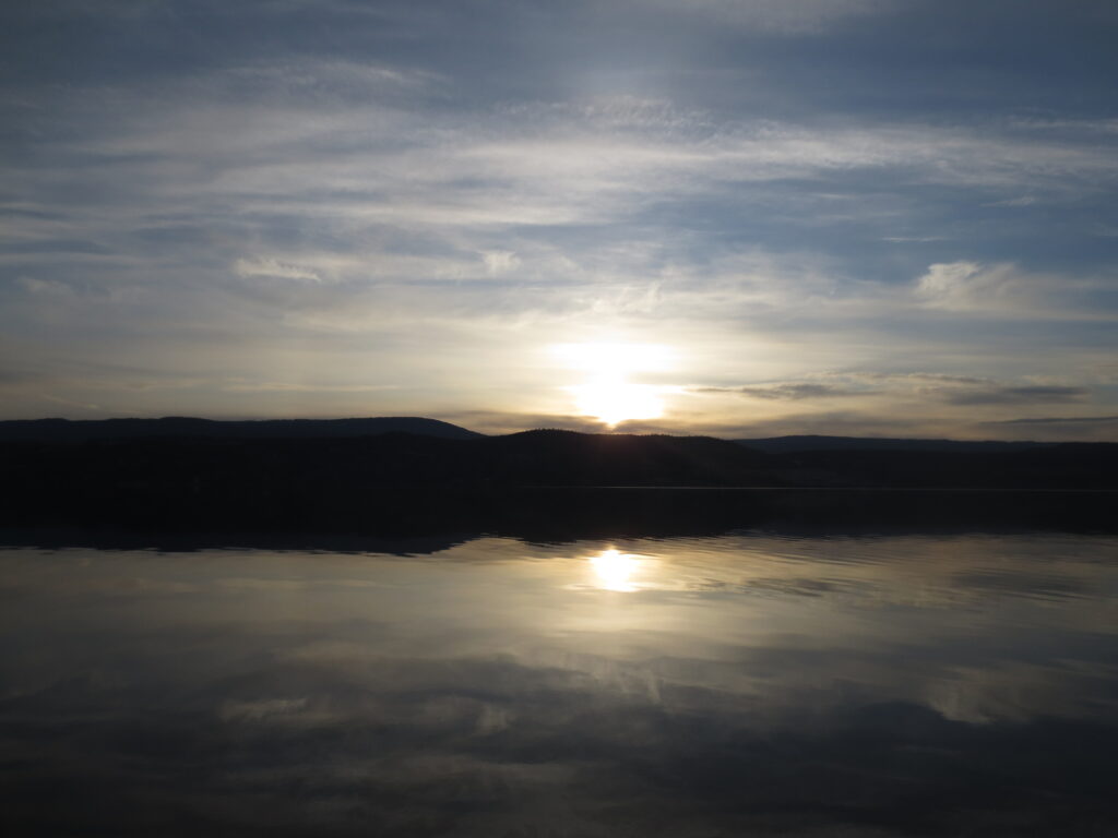 Sunrise reflected on the still surface of a lake, an image of the observer and the observed as one field