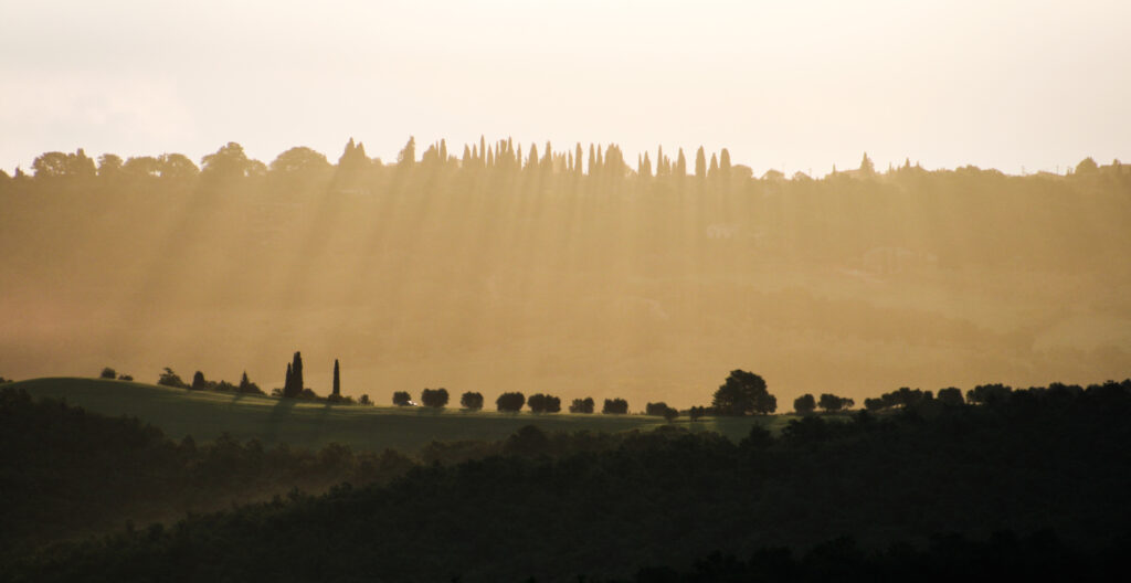 Morning light and crepuscular rays over a Tuscan valley, an image evoking the philosophy of attention