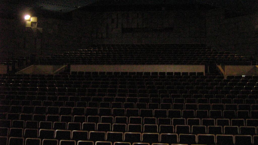 Auditorium seen from the stage, rows of empty seats facing the speaker, evoking very long seminar days