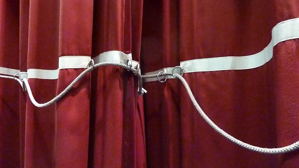 A theatre stage curtain parting at the centre, a metaphor for looking behind the scenes of channeling on stage