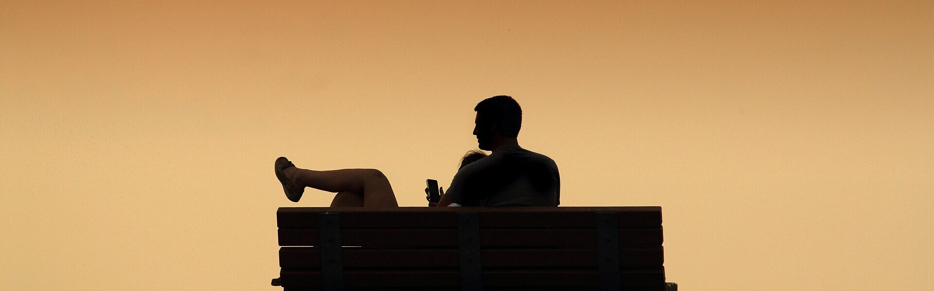 Two people sitting close together at sunset, symbolising love as the felt experience of non-separation in Ad Unum Energy Healing