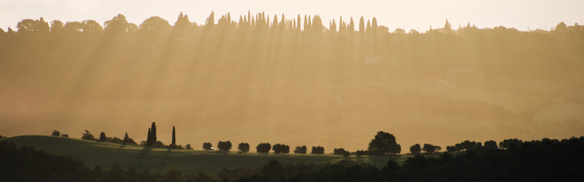 Morning light and crepuscular rays over a Tuscan valley, an image evoking the philosophy of attention