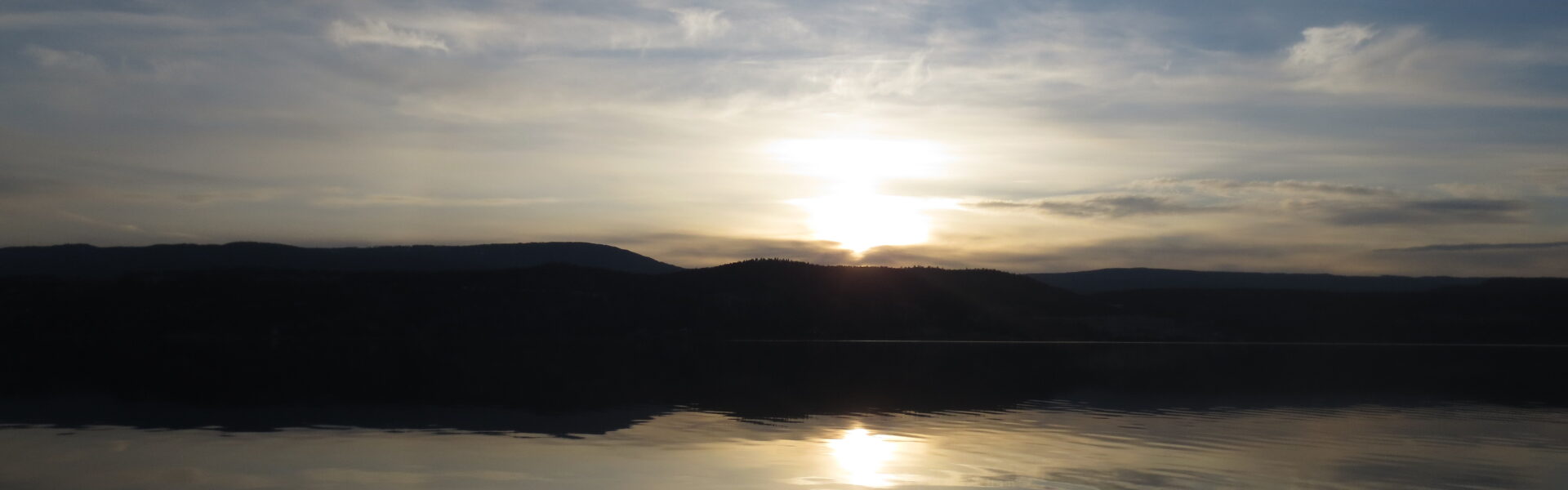 Sunrise reflected on the still surface of a lake, an image of the observer and the observed as one field