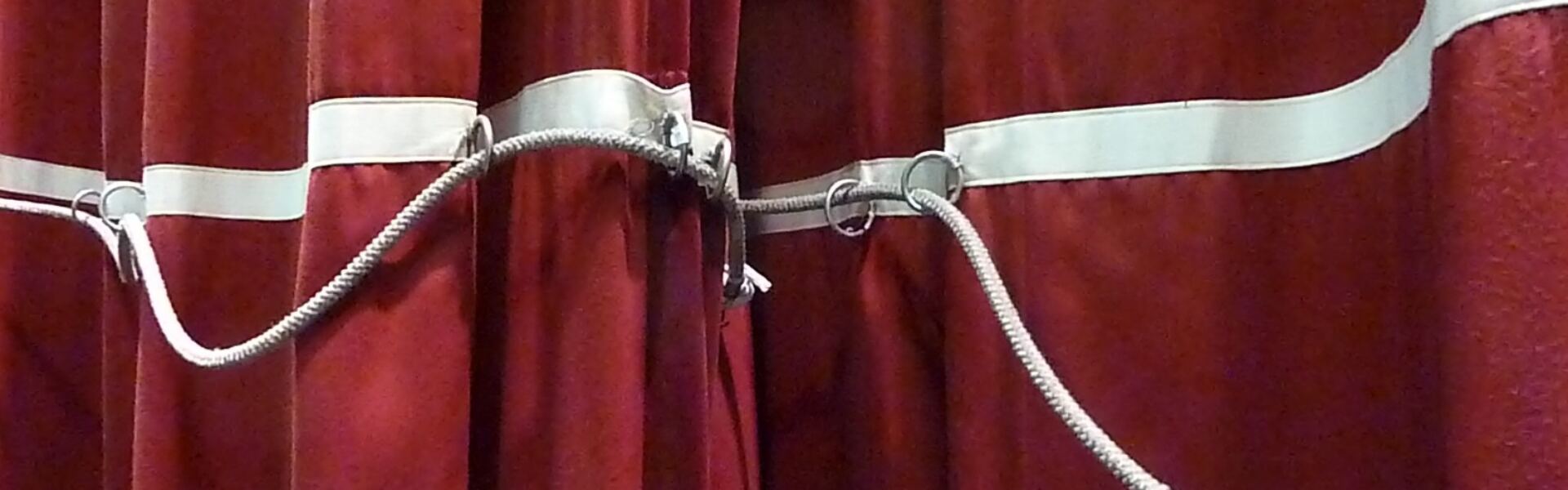 A theatre stage curtain parting at the centre, a metaphor for looking behind the scenes of channeling on stage